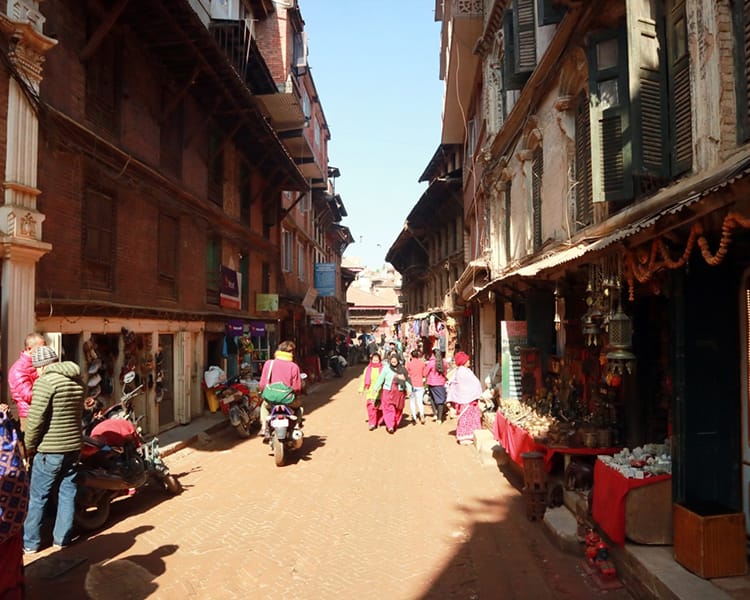 People walk down the colorful street of Sukuldhoka Bazar