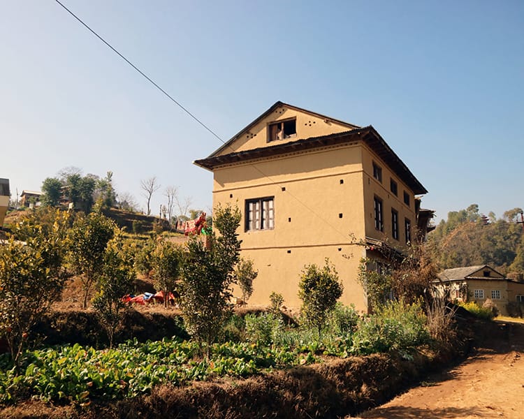A traditional clay home surrounded by orange trees in Balthali, Nepal