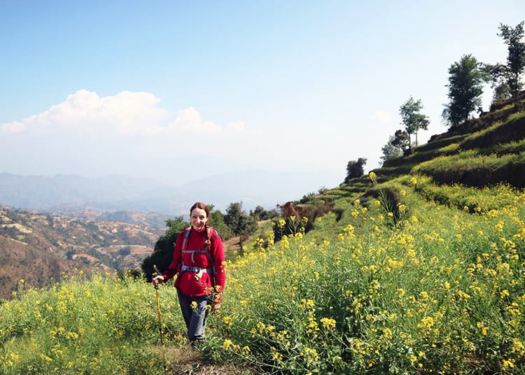 Michelle Della Giovanna from Full Time Explorer stands in a field of mustard flowers during the Kathmandu Valley Trek