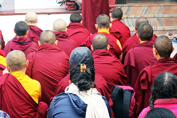 Monks dressed in maroon and yellow sit chanting before Losar at Namo Buddha Monastery in Nepal