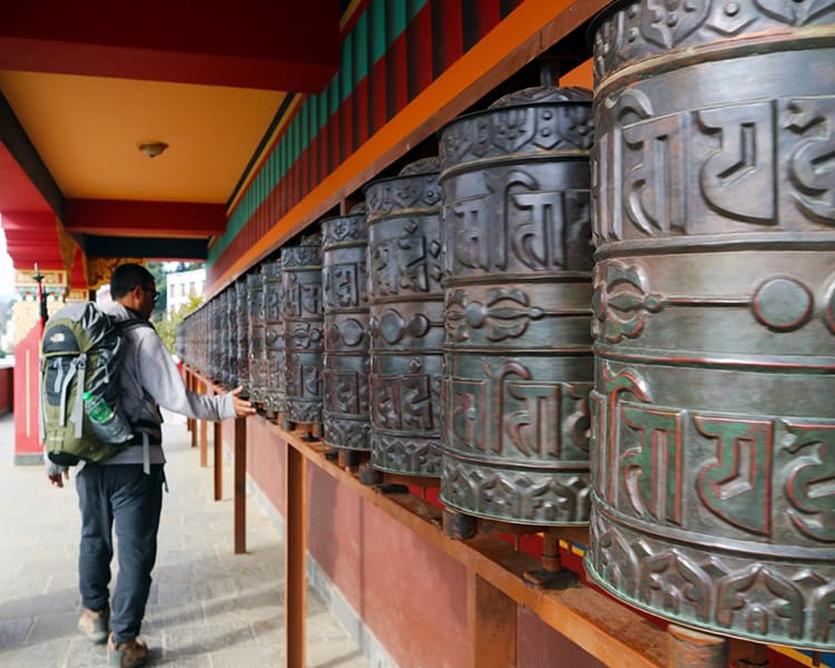 A trekker turns the prayer wheels at Namo Buddha Monastery