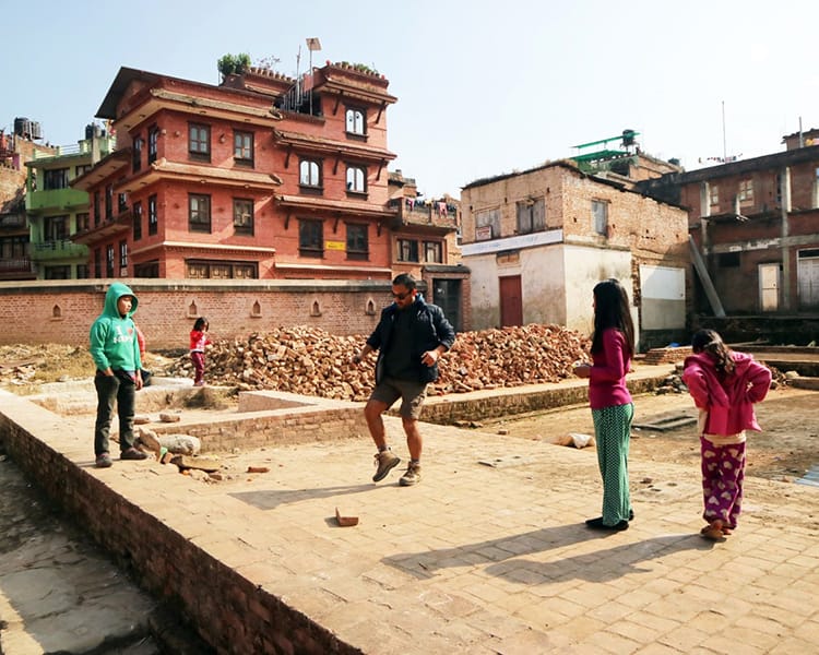 A man and three children play hacky sack where the old palace once stood in Panauti