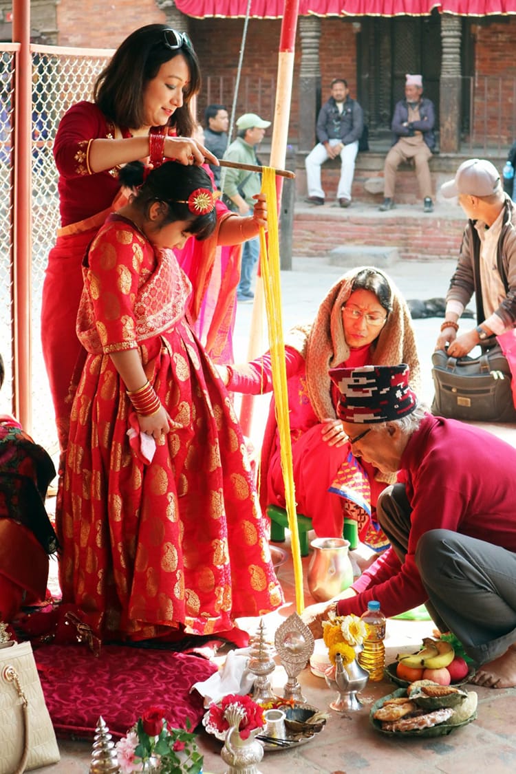 A young Nepali girl has thread wrapped from her head to her feet by a priest at an Ihi ceremony in Kathmandu