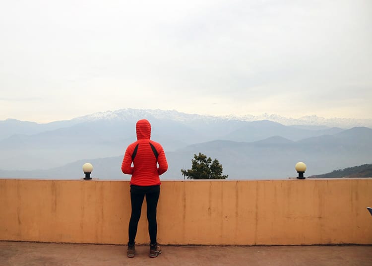 Michelle Della Giovanna from Full Time Explorer stands on a balcony with the Himalayan mountains in the distance