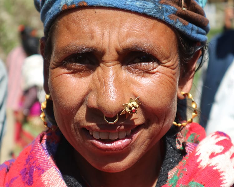 A beautiful woman with an elaborate nose ring smiles for a photo