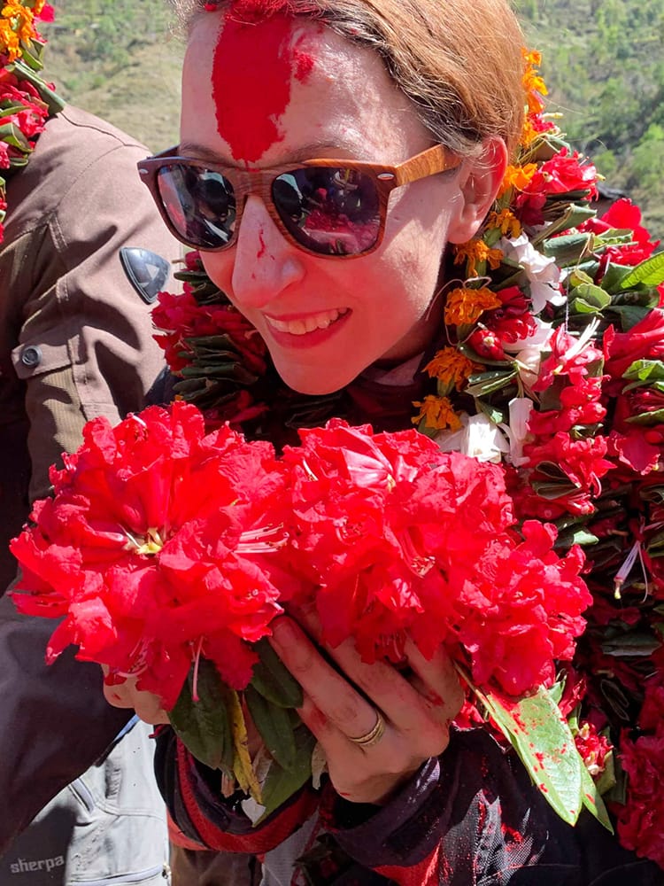 Michelle Della Giovanna from Full Time Explorer is showered with homemade flower garlands and red tikka powder as she enters the village