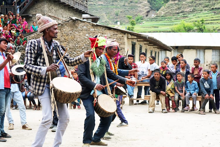 Local musicians play drums in the middle of the village square as entertainment