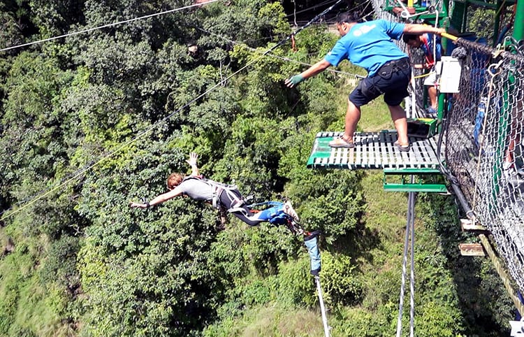 Michelle Della Giovanna from Full Time Explorer jumps off a suspension bridge while bungy jumping in Nepal