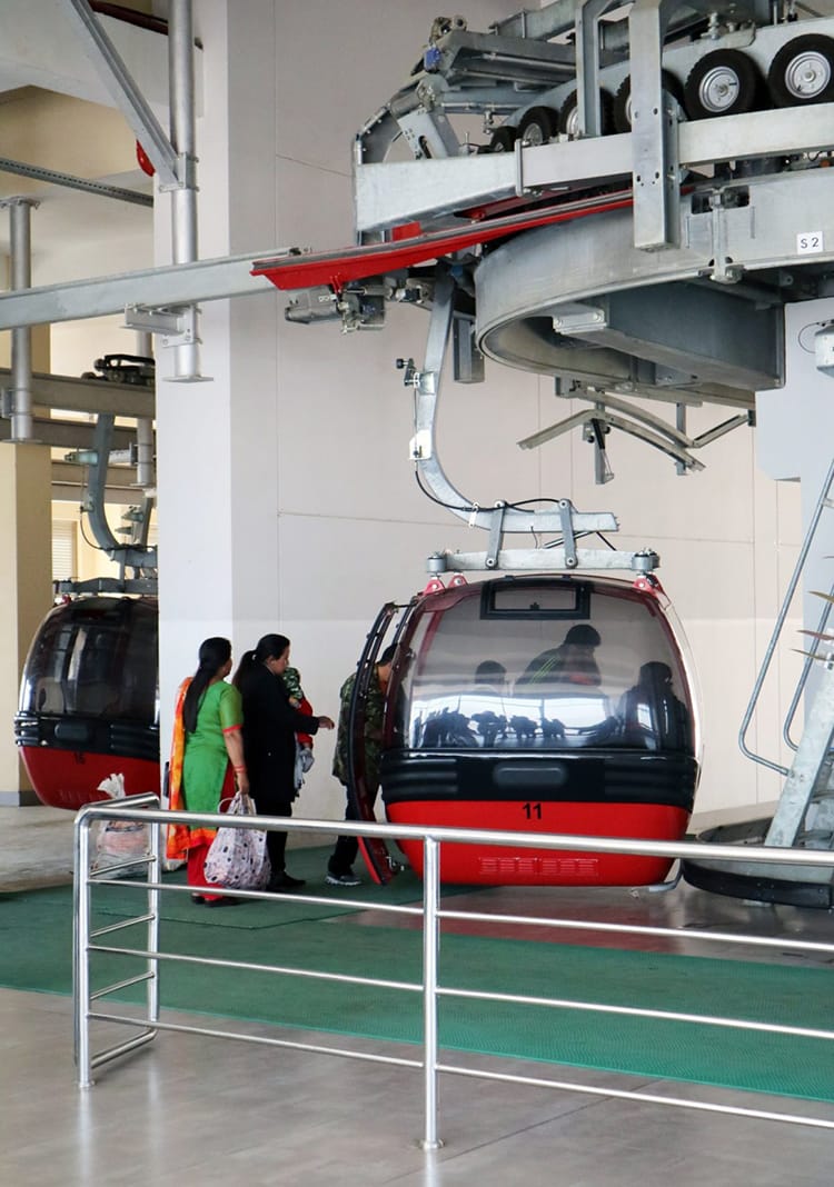 People board a red cable car on the way up Chandragiri Hills