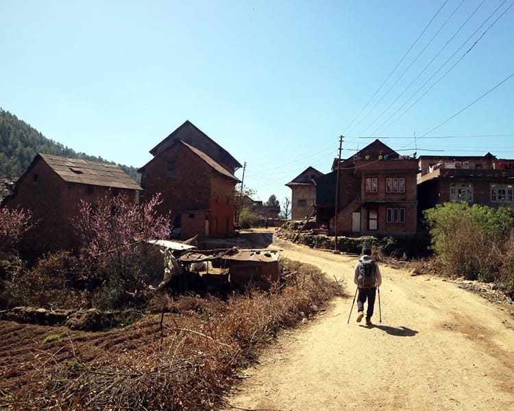A trekker walks up the dirt road in Chitlang