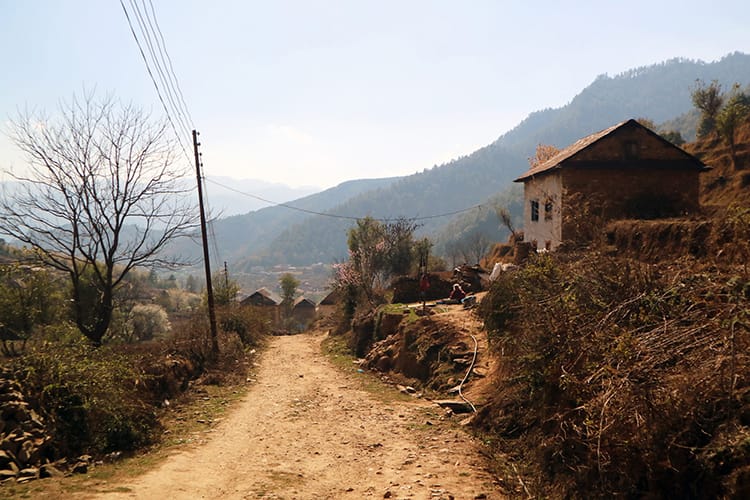 A dirt road goes through Chitlang with beautiful old stone homes on each side.