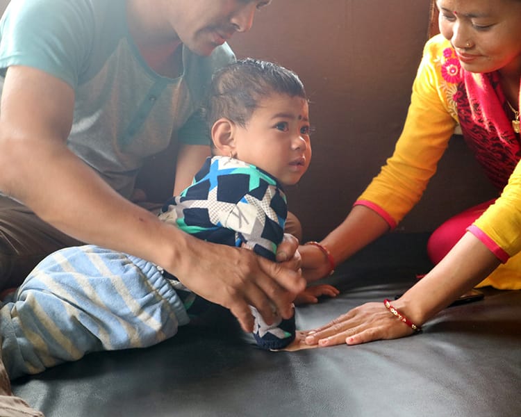 A physical therapist helps a toddler stretch and hold poses to strengthen his arms