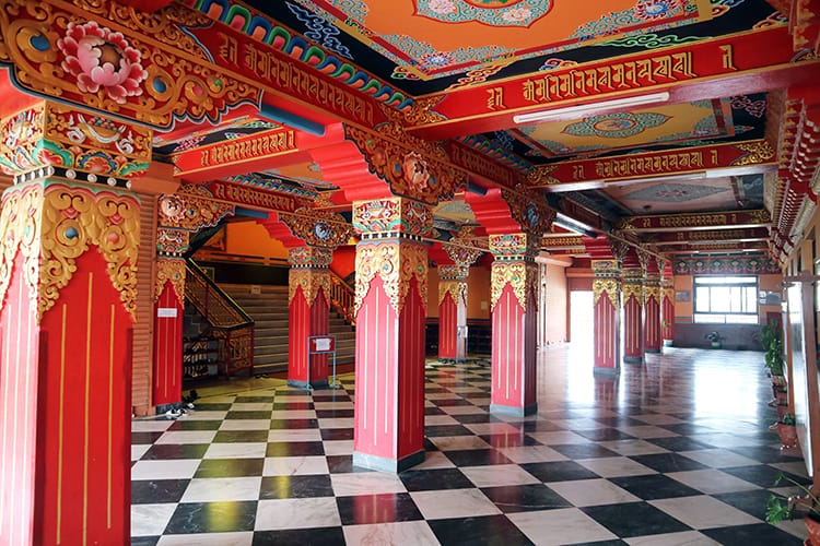 Inside Namo Buddha Monastery in Nepal where intricate and brightly painted red columns line the entry