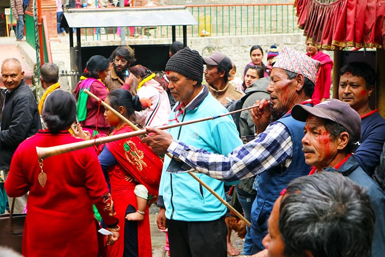 Men play long trumpet instruments with sindoor powder smeared on their cheeks