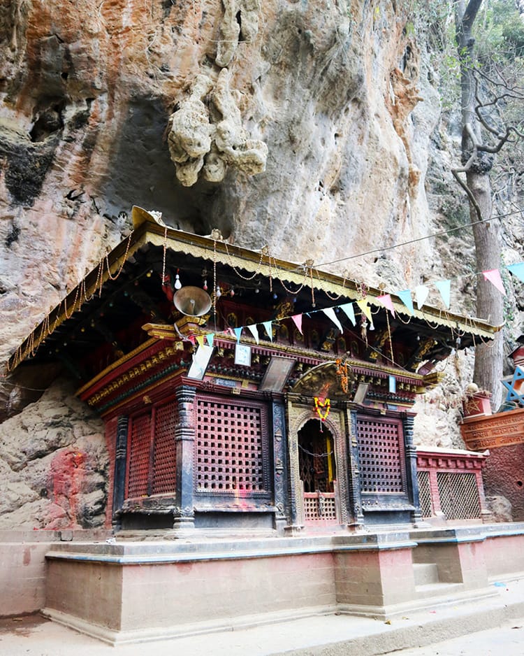 A temple building built on the side of a rock wall next to Yanglesho Cave