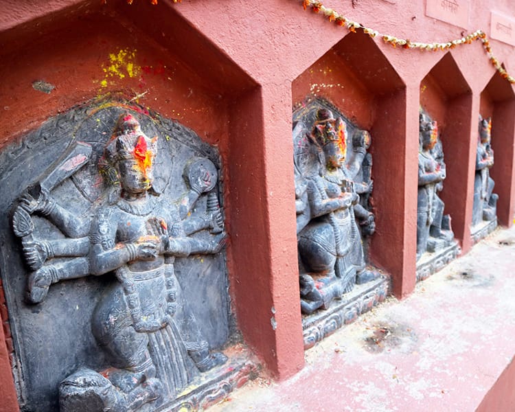 Small statues of gods line a wall at the original Dakshinkali Temple