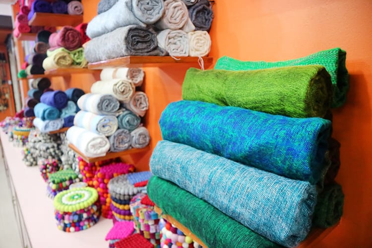 Brightly colored scarves stacked on a shelf in a souvenir shop in Nepal