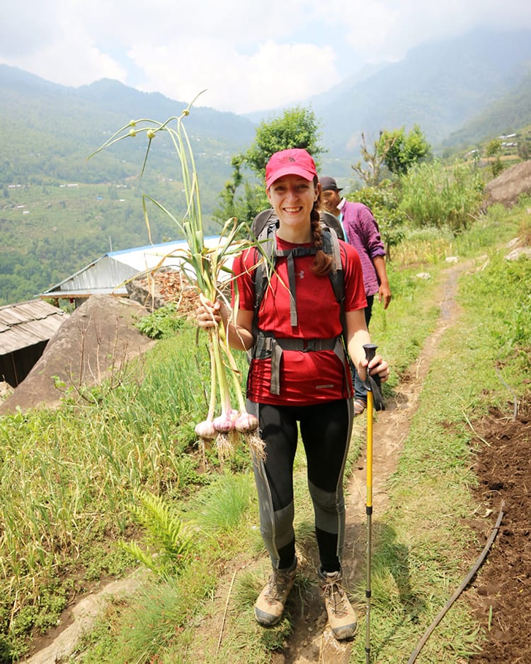 Michelle Della Giovanna from Full Time Explorer smiles while holding four beautiful garlic heads that were given as a gift