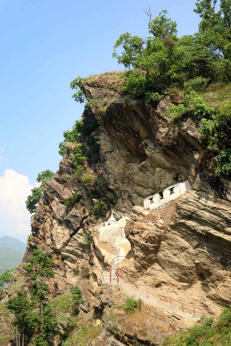 A small white temple sits on the side of a steep mountain