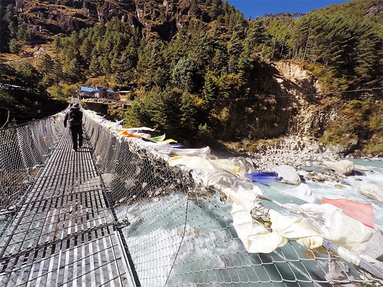 A trekker crosses a suspension bridge on the way to Everest Base Camp