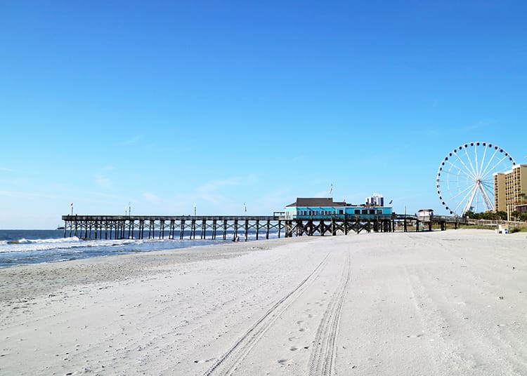 One of the piers and a ferris wheel in the distance beyond the clean sands of Myrtle Beach