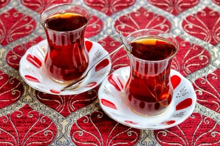 Two turkish tea cups sit on a mosaic table