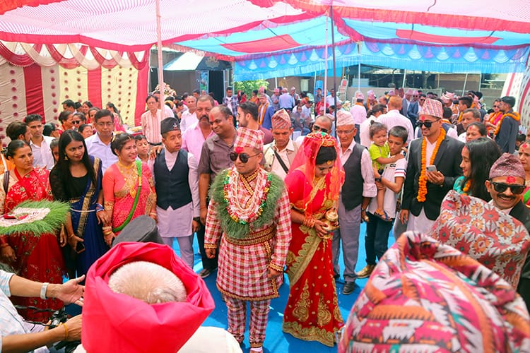 Nepali people gather for a wedding while wearing traditional Nepalese dress