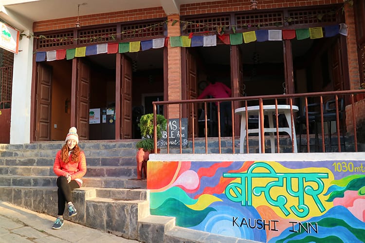 Michelle Della Giovanna from Full Time Explorer sits in front of a mural at Bandipur Kaushi Inn