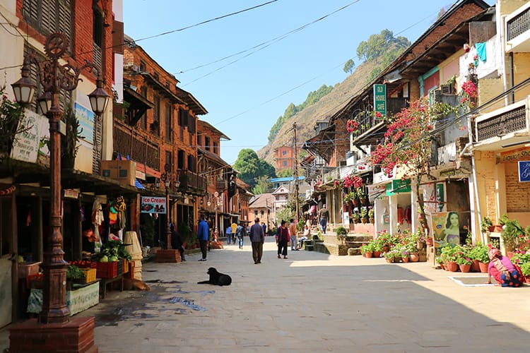 People walk down the main street of Bandipur on a sunny day