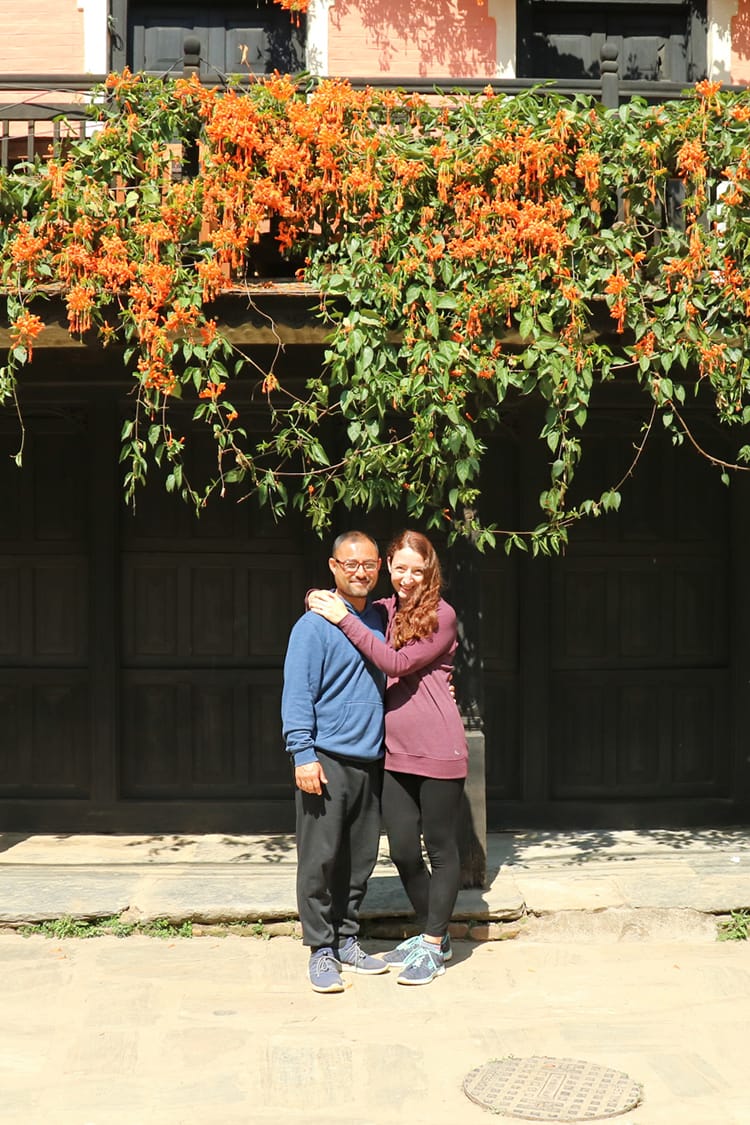 Michelle Della Giovanna from Full Time Explorer and her husband stand under the orange flowers hanging from above