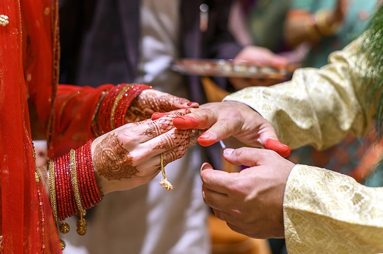 A Nepali bride puts a ring on the grooms hand while wearing a Kusha ring