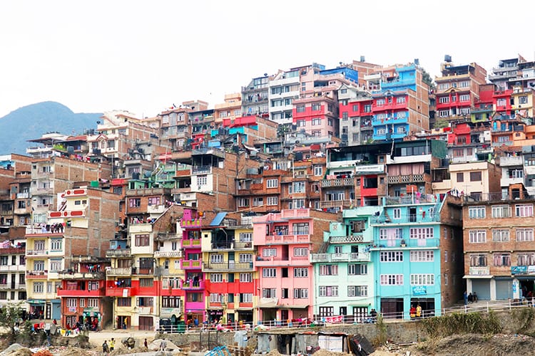 Brightly colored houses stacked on a steep hill in Kirtipur 