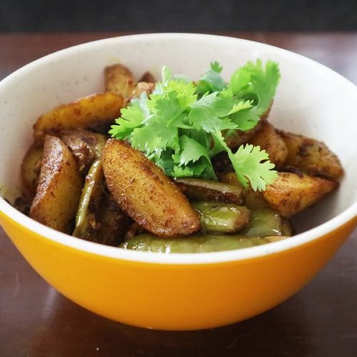 A dish of Nepalese dry brinjal curry with cilantro on top as garnish