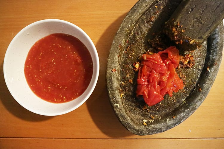 The tomato skins separated from the liquid tomato and added to the mortar to be ground up with the spices