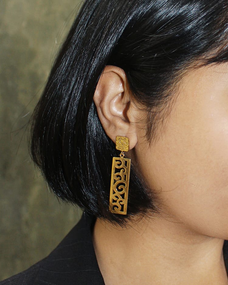 A women wearing rectangular gold plated earrings