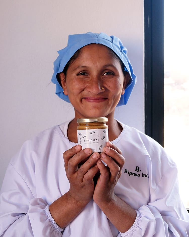 A worker in the factory holds a jar of Sachai peanut butter