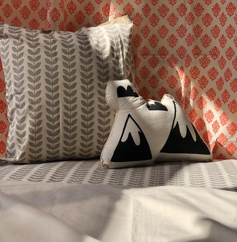 Bedding made by Cotton Mill Nepal featuring a modern striped design in gray and a cream and black pillow with the Himalaya mountains