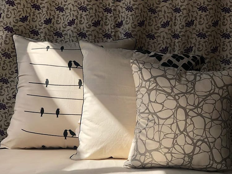 Pillow covers made by Cotton Mill Nepal featuring birds on a telephone wire and an abstract modern print in gray