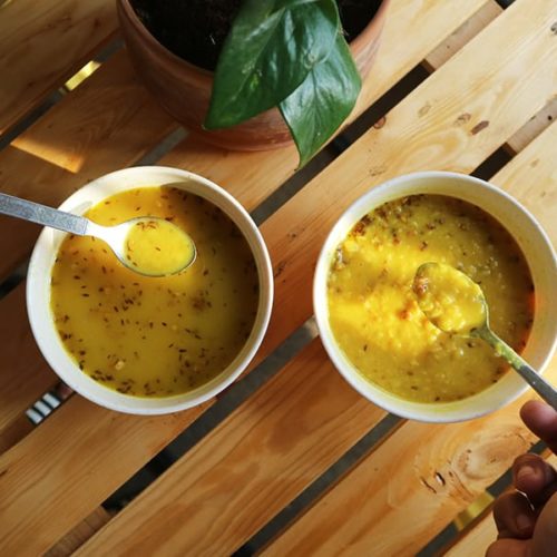 Two bowls of yellow dal fry. One a thin soup, and one a thick soup