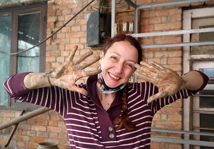 Michelle Della Giovanna from Full Time Explorer holding up her hands covered in clay after taking a pottery class in Kathmandu
