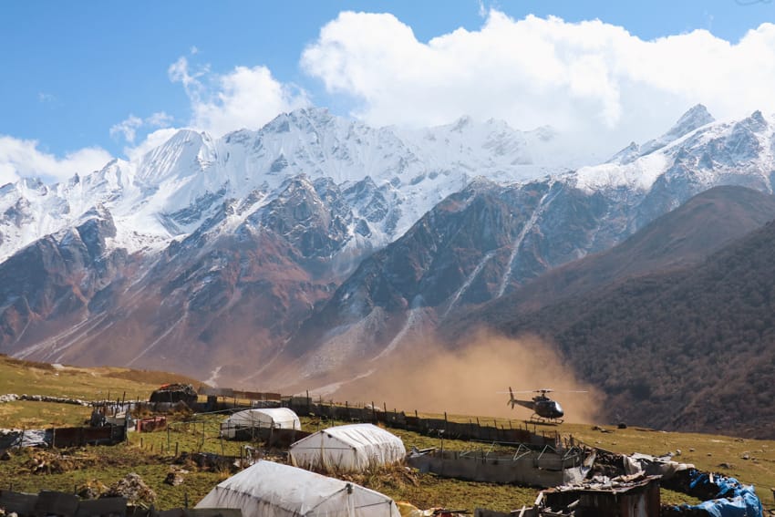 A helicopter lands in Kyanjin Gompa