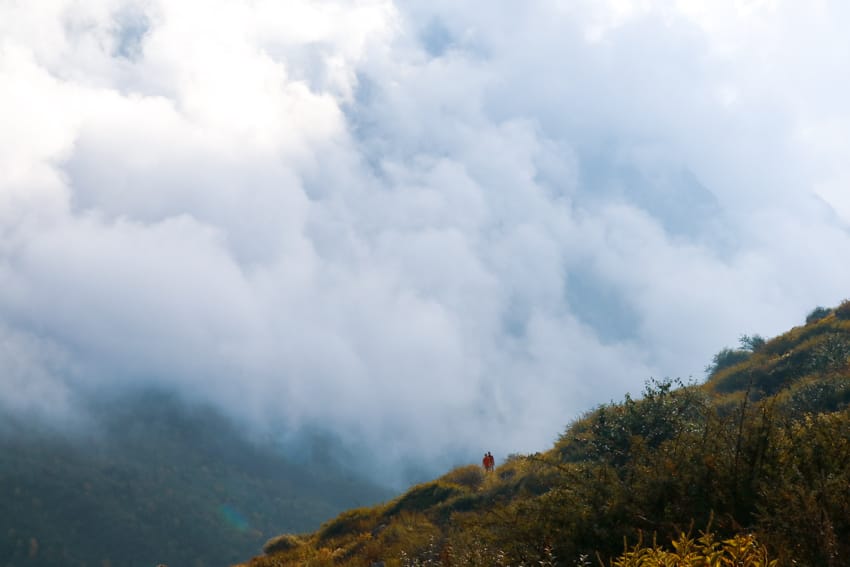 Two trekkers walk through clouds on the way to Langtang