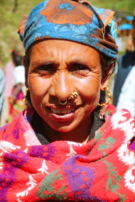a Magar woman wearing a gold nose ring and earrings