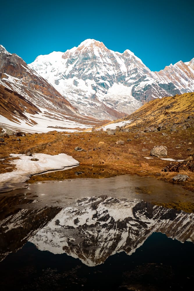 The Annapurna Mountain Range reflecting in a puddle of water