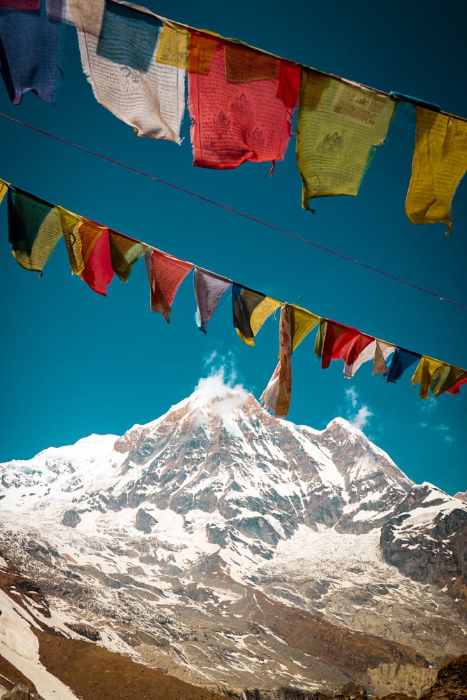 Annapurna Base Camp view with white mountains and prayer flags fluttering in the breeze