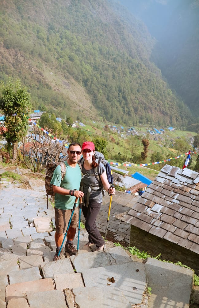 Michelle Della Giovanna from Full Time Explorer and her husband pose in front of Chomrong village on the way to ABC
