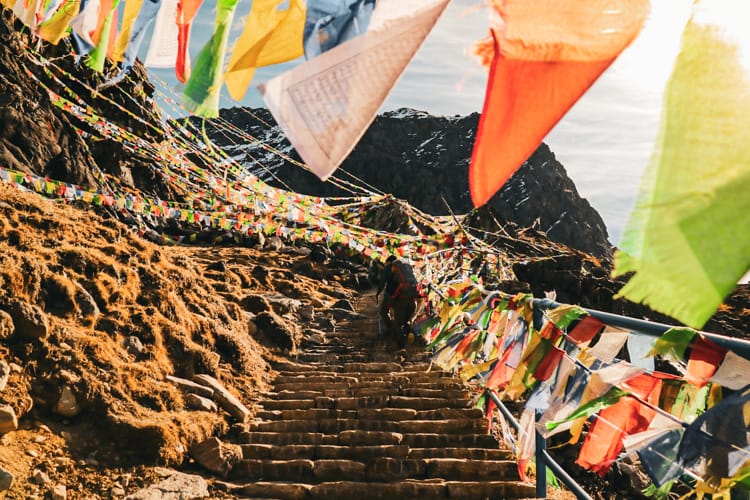 Prayer flags line a staircase leading to the temple where people collect water by Gosaikunda Lake in Nepal