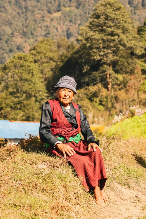 An old woman sits on the side of the road on the way to Tarkeghyang Nepal along the Helambu Trek