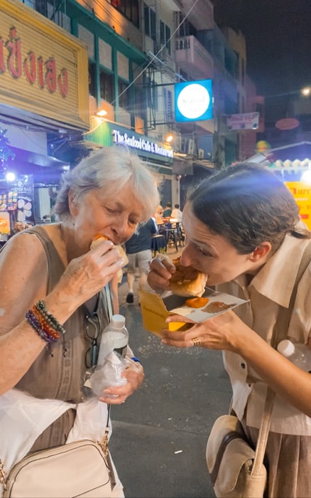 Michelle and her mom biting into a bun filled with jelly at the Chinatown night market