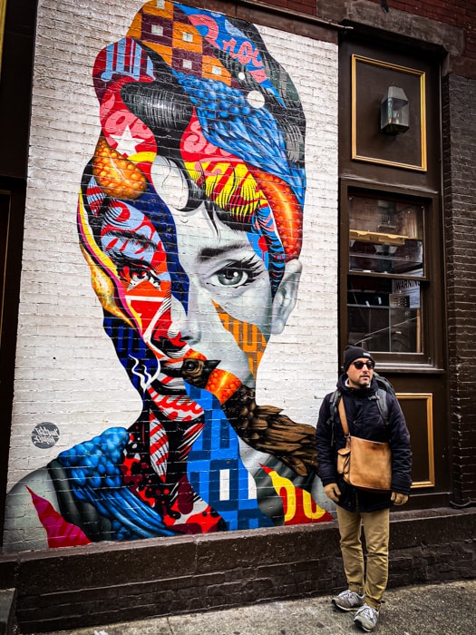 suraj in front of a street art mural of Audrey Hepburn